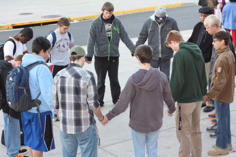 Students hold hands as they pray