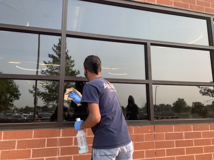 An ABM Maintenance Worker sanitizes a lunchroom window.  