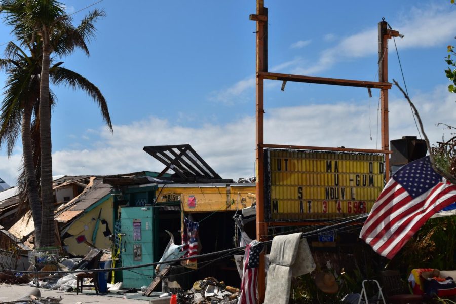 A toppled over building lies ruined on the ground with a broken sign that once told the name of a store.