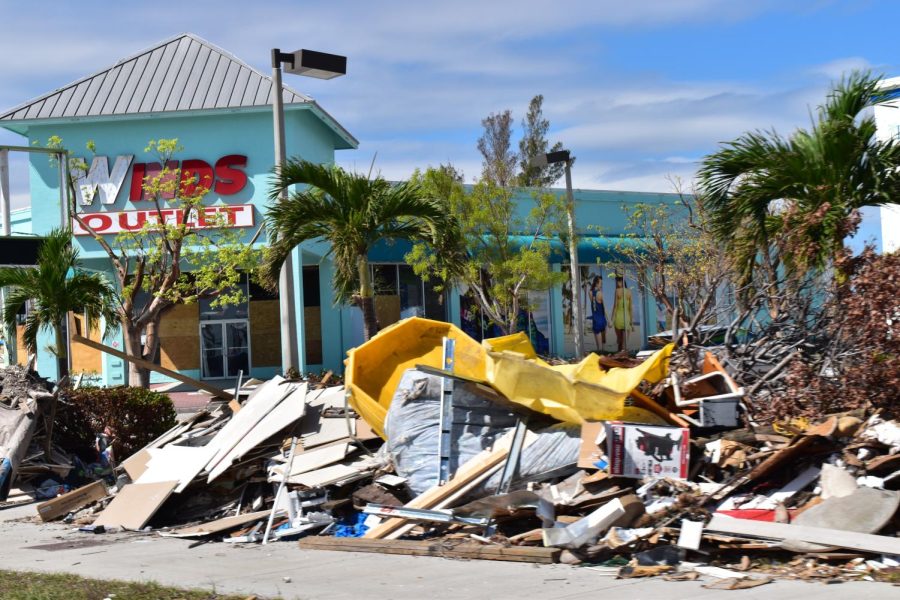 A store with boarded windows sits behind a pile of various debris from hurricane Ian.