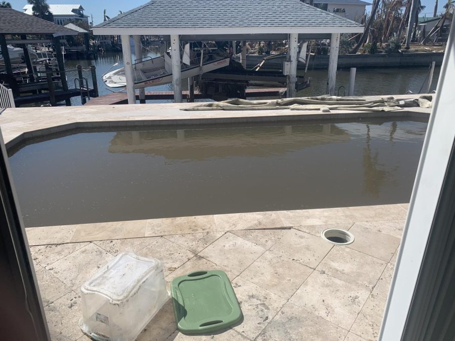 A boat blown onto another boat during the hurricane sits behind a pool filled with murky water in the backyard of Kim’s house.