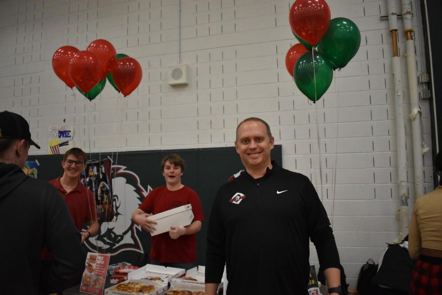 Smoky Hill teacher and DECA coordinator David Decker stands in front of students selling cinnamon rolls.